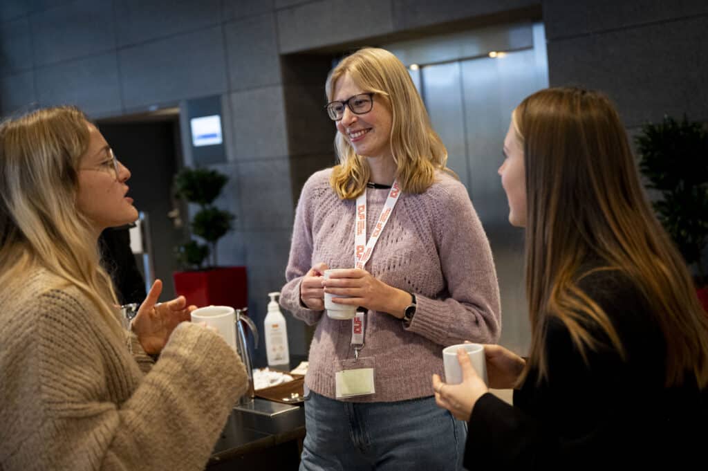 Gruppe af tre unge kvinder taler sammen.