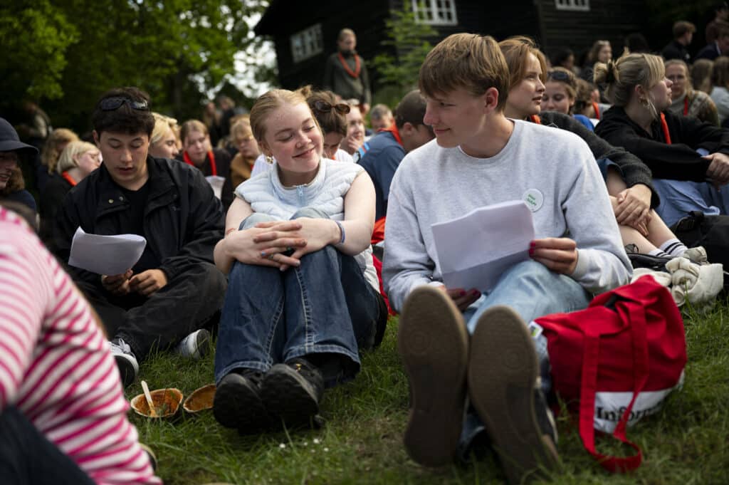 Ung mand og ung kvinde taler sammen på græsset.
