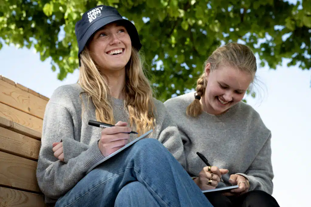 To unge kvinder skriver på notesblokke