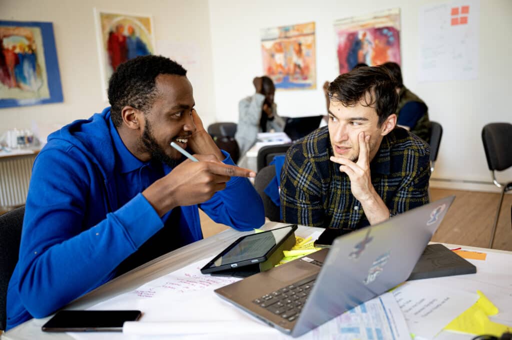 To unge mænd snakker foran computer