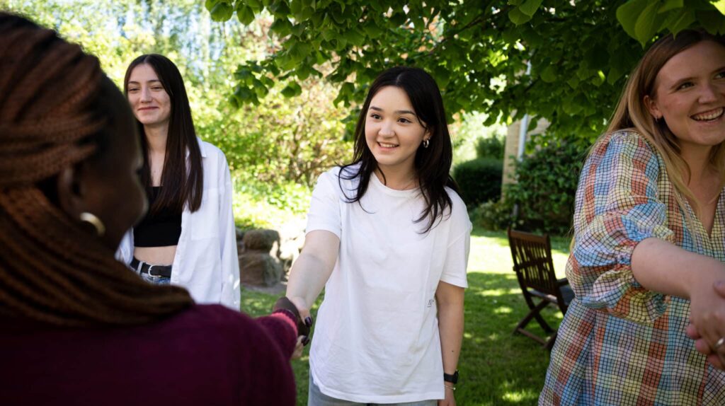 Ung kvinder giver hånd til ung kvinde